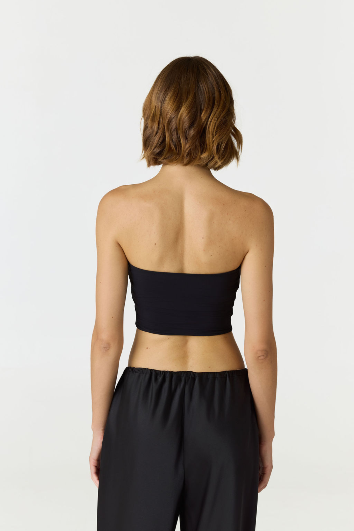 Elevate your warm-weather wardrobe with the Edie Bandeau Top in Black from AOCO. This chic strapless design offers a flattering fit and endless style possibilities.