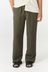 A person wearing loose, wide-leg olive green pants with a cream shirt and black sandals, shown from the waist down against a plain white studio background.