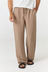 A person wearing loose, wide-leg taupe pants with a drawstring waist, paired with a white top and black sandals, shown from the waist down against a plain light background.